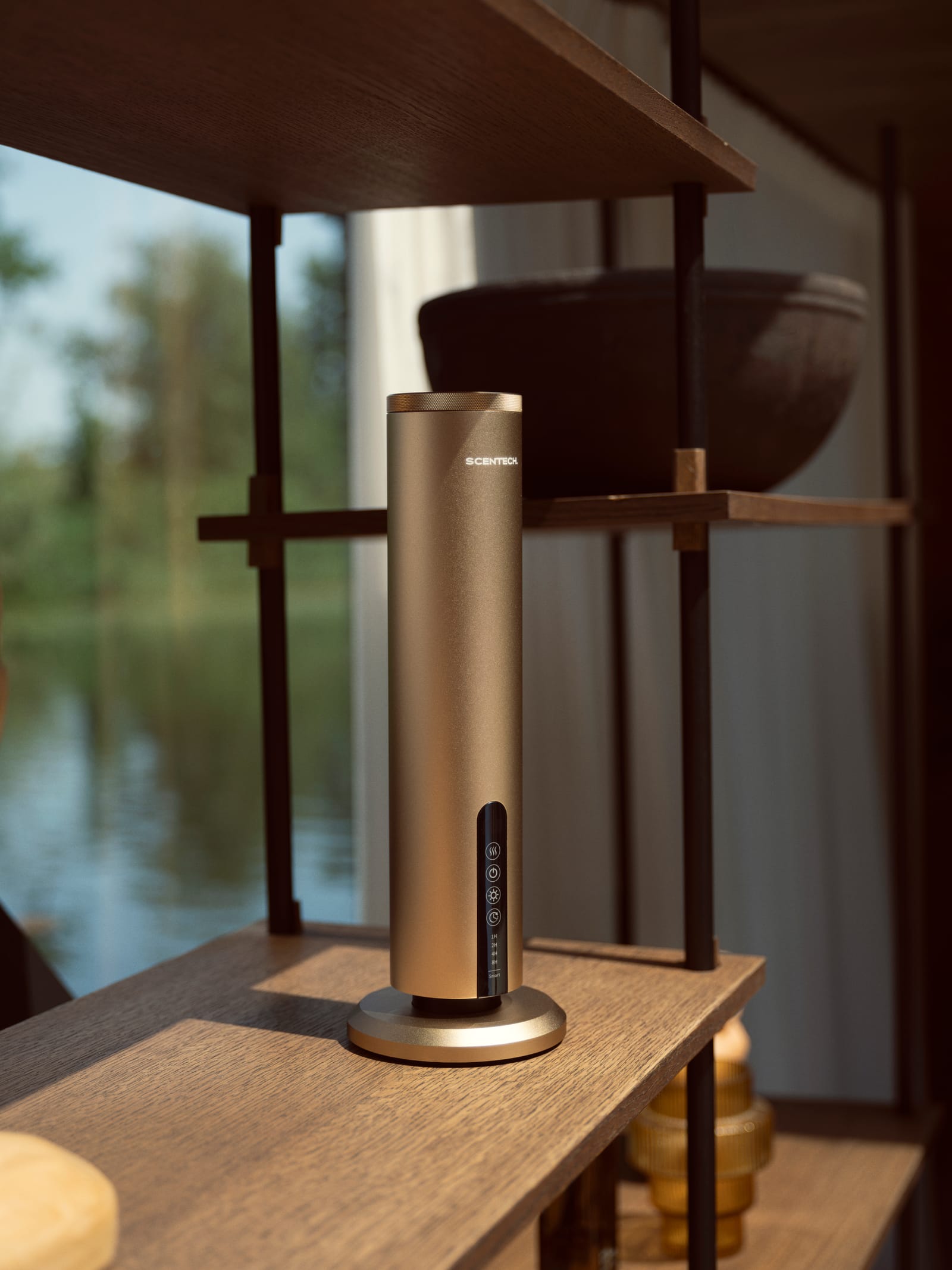 Scentech Smart Aroma Diffuser Pro op een houten kast voor een raam met uitzicht op het water